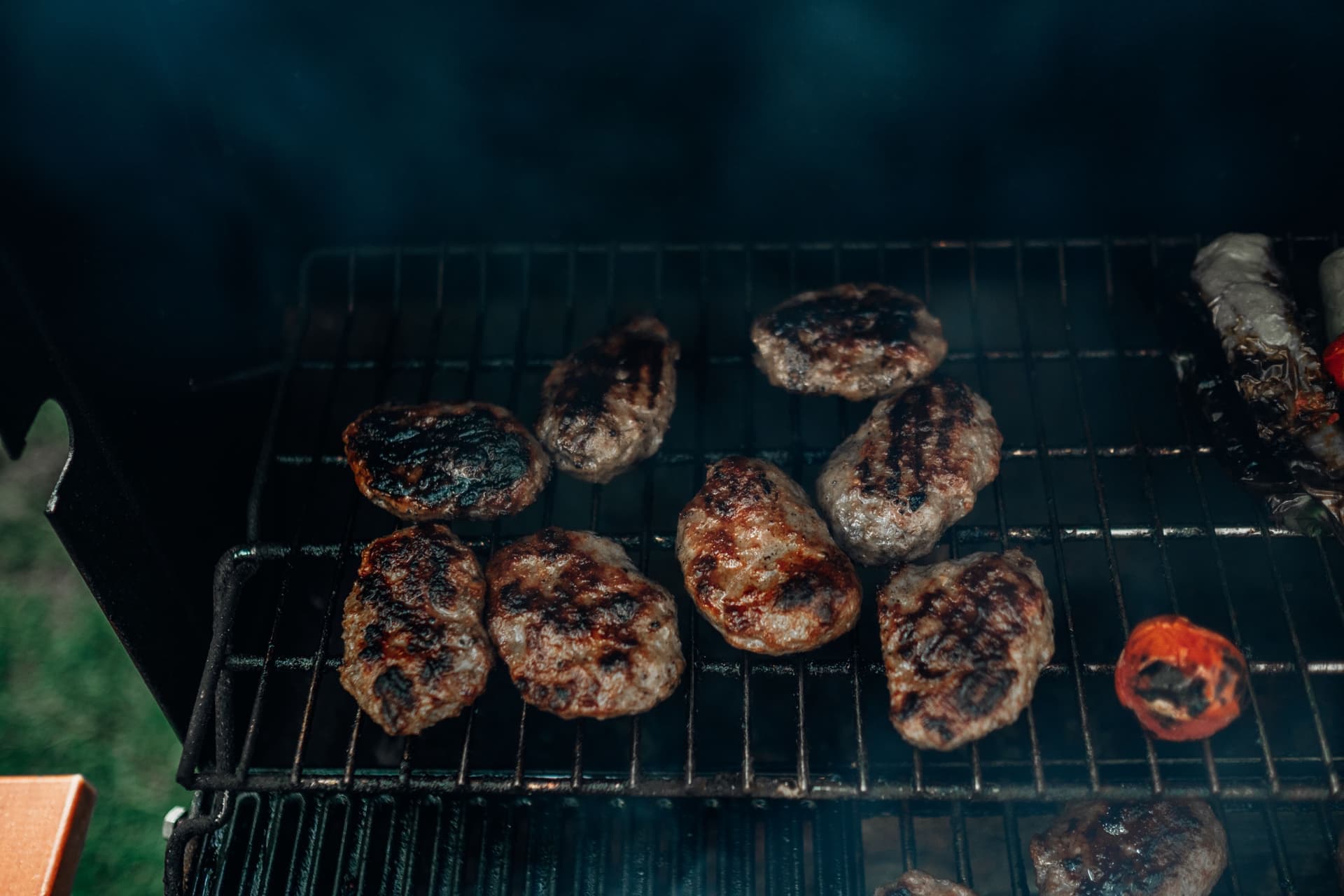 Burgers searing over glowing charcoal