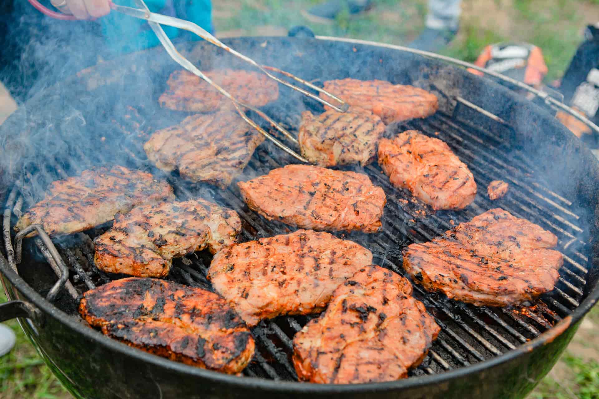 A meat thermometer probe checking the temperature of food on a grill