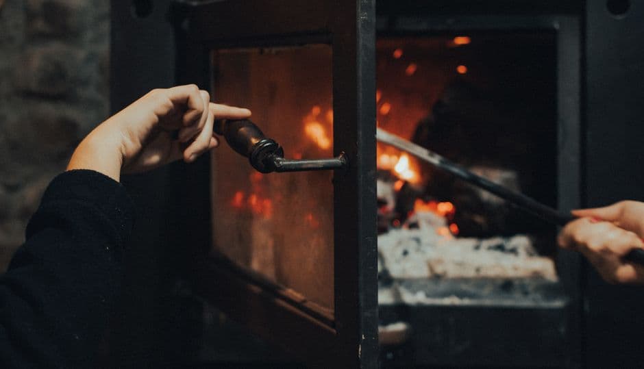 Hands tending a fire with the logs pushed together