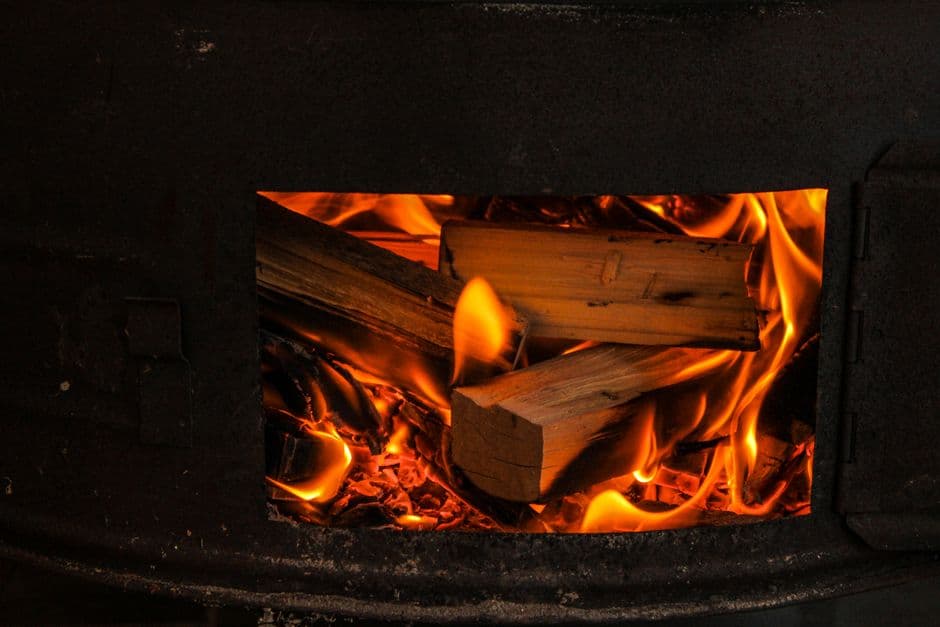 Firewood burning behind the door of a wood stove